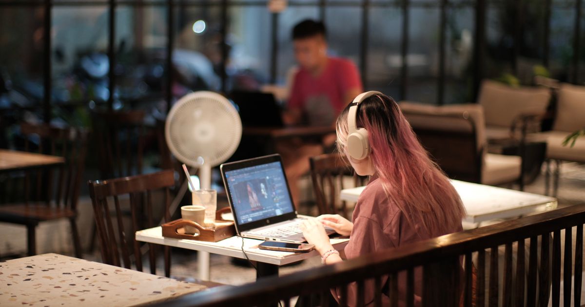 A woman editing video on a laptop in a cafe