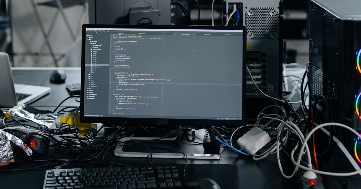 A desktop monitor showing a code editor beside a keyboard and mouse