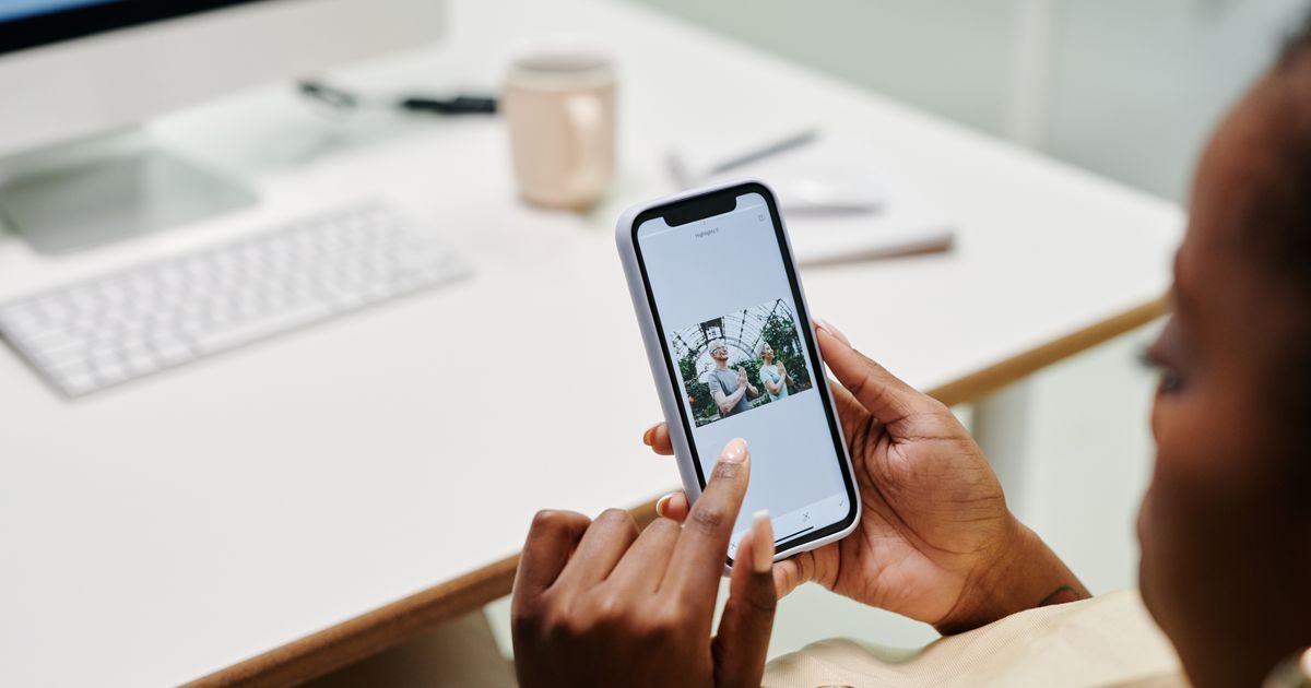 Hands using a smartphone beside a computer