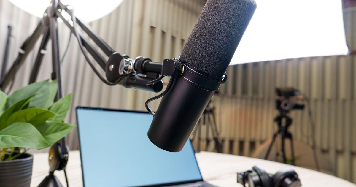 A podcast studio with a microphone, laptop, and headphones