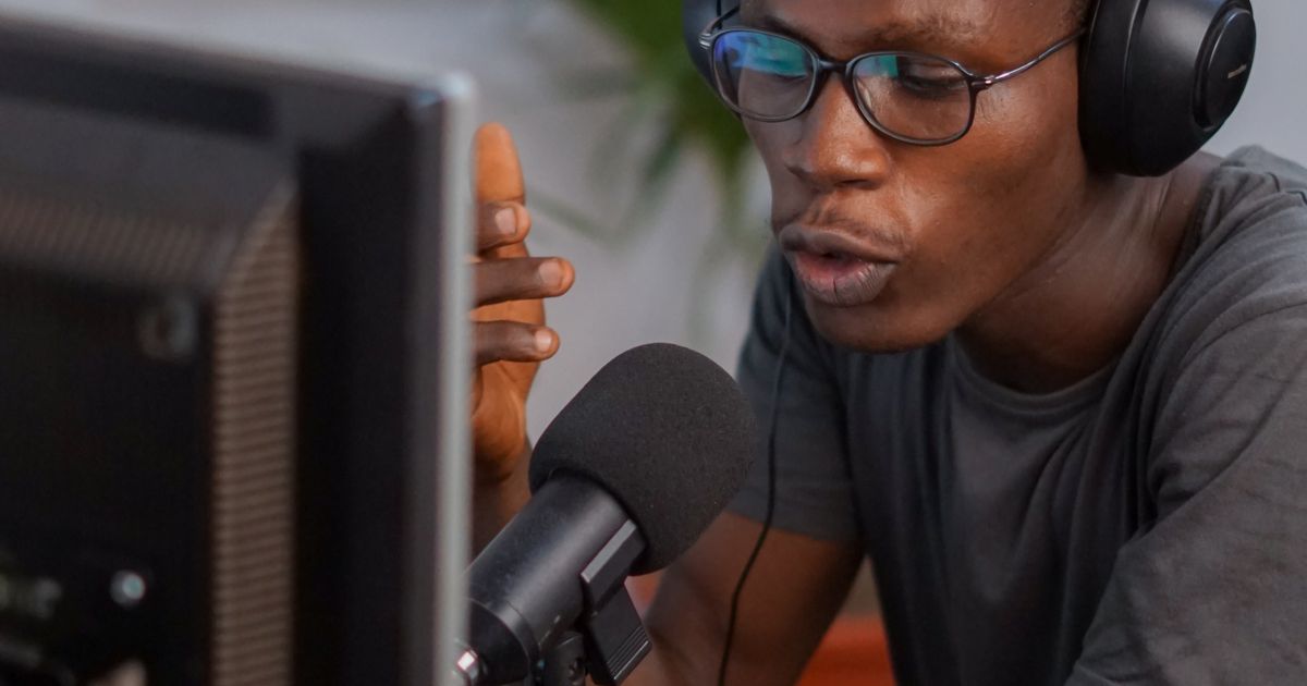 A person wearing headphones and speaking into a microphone at a desk